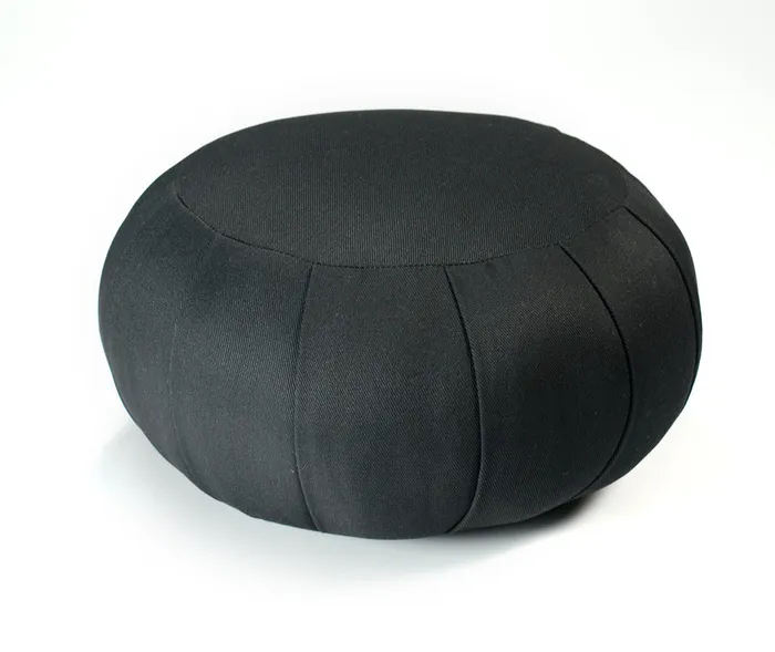 Black pleated zafu meditation cushion on a plain background